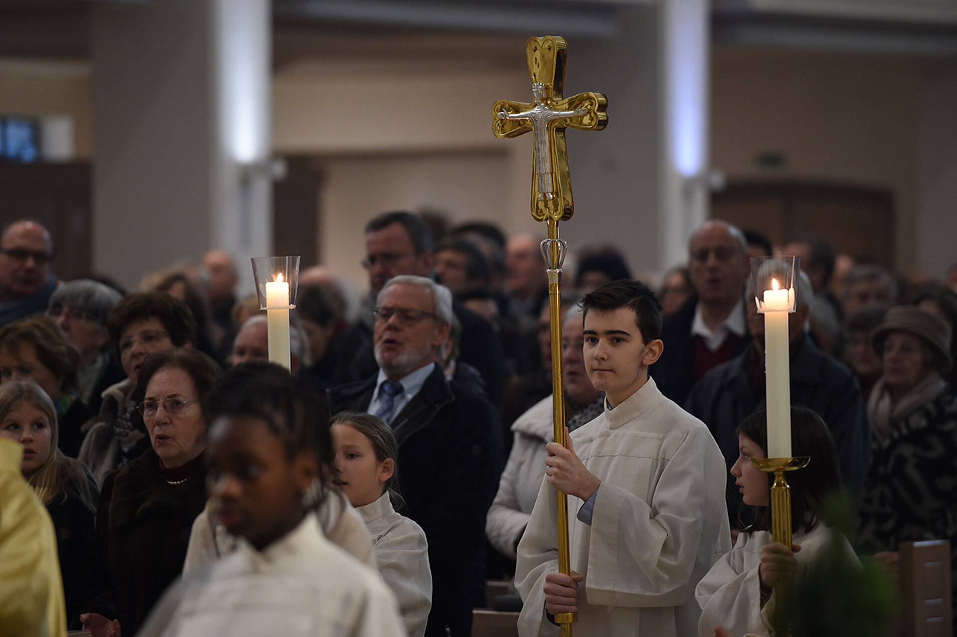 Ein Ministrant trägt das Kreuz an Weihnachten